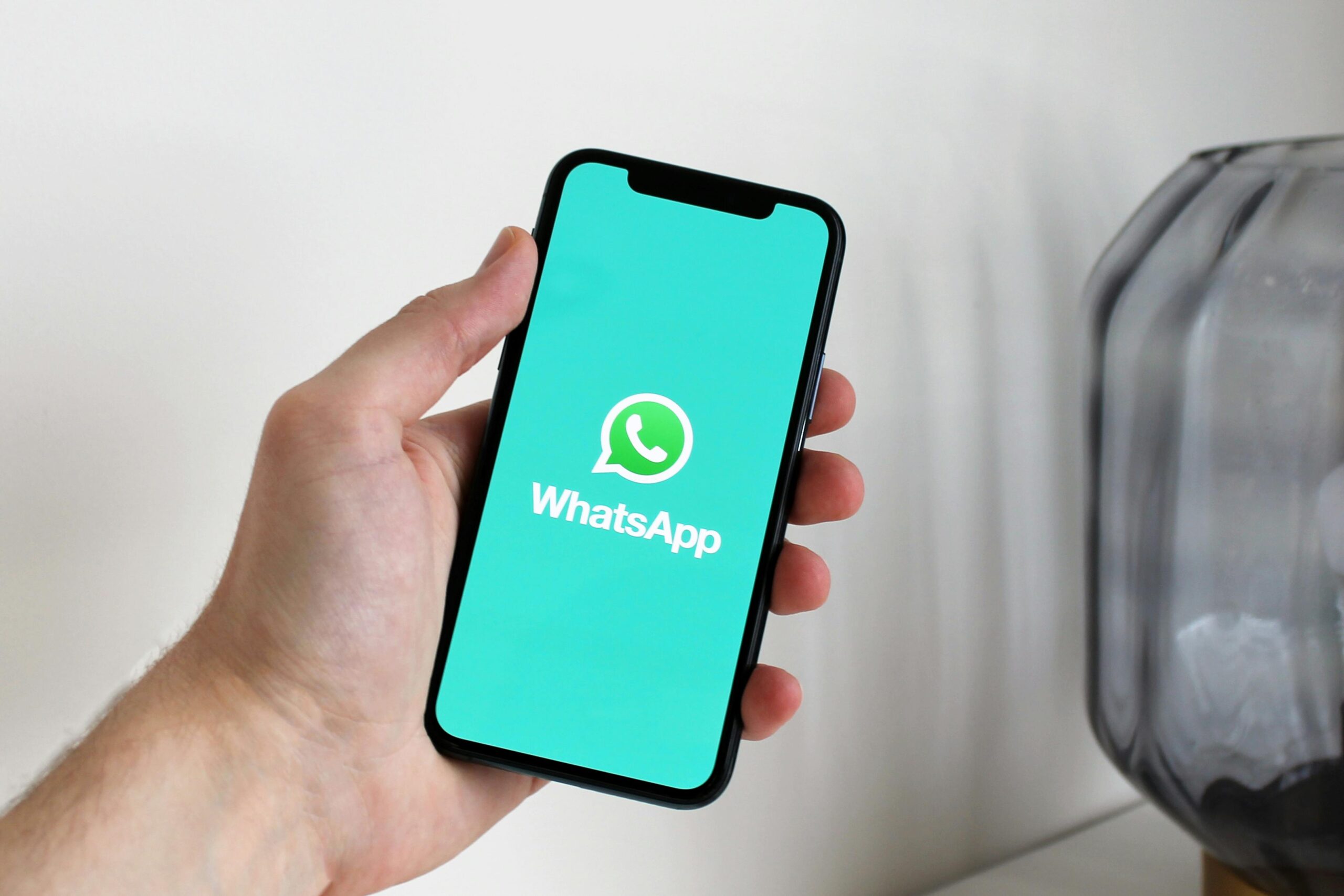 Close-up of a hand holding a smartphone displaying the WhatsApp app screen.